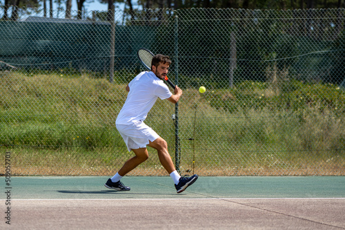 Tennis player hitting backhand at ball