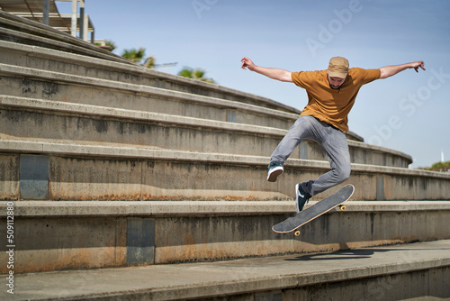 A young man doing an ollie 360 flip with his skateboard on some bleachers
