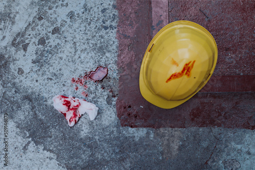 Helmet and tissue with blood stains and blood on the floor, work accident concpet.