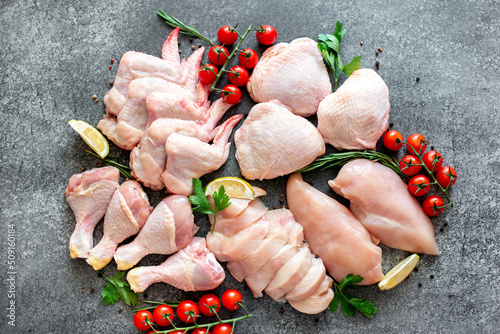 Set of raw chicken fillet, thigh, wings, strips and legs on a stone background of a culinary table with spices