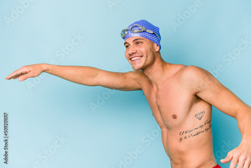 Young caucasian swimmer man isolated on blue background