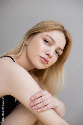 Portrait of young blonde woman looking at camera isolated on grey.