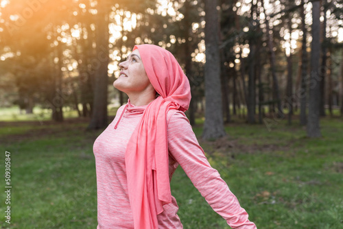 caucasian mature woman wearing pink cancer scarf screaming proud, celebrating victory and success very excited in nature