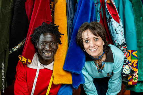portrait of entrepreneurs tailors of small company among their clothes produced by hand, collaboration between different cultures and small business