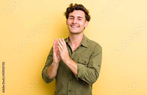 young handsome man feeling happy and successful, smiling and clapping hands, saying congratulations with an applause