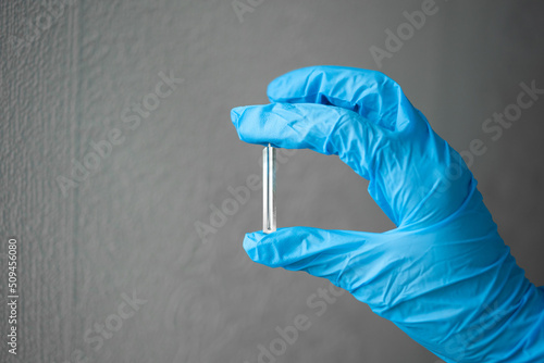 A nurse wearing blue medical gloves holds a lancet to draw blood