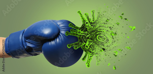 Hand in boxing glove kicking cigarette on green background. Concept of immunity