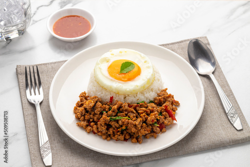 Spicy minced pork pad kra pao, minced pork stir-fried with holy basil leaves, served with plain cooked rice and a fried egg, a popular Thai single dish served from street food carts to restaurants.