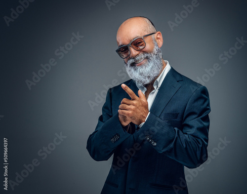 Shot of happy elderly businessperson with beard and sunglasses dressed in stylish suit.