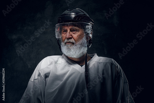 Shot of old sportsman with long beard dressed in white sportswear and helmet.