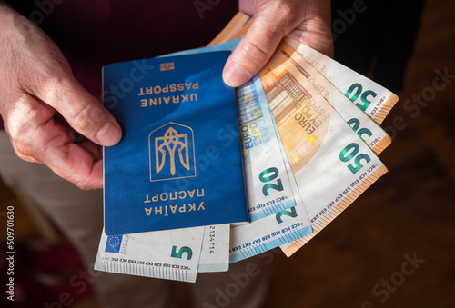 a woman pensioner holds in her hands a Ukrainian biometric passport with Poland zloty banknotes
