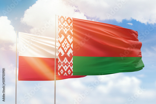 Sunny blue sky and flags of belarus and poland
