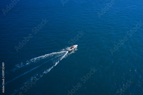 Top view of the boat. Top view of a white boat sailing in the blue sea. A boat with a motor on blue water. Aerial view luxury motor boat.