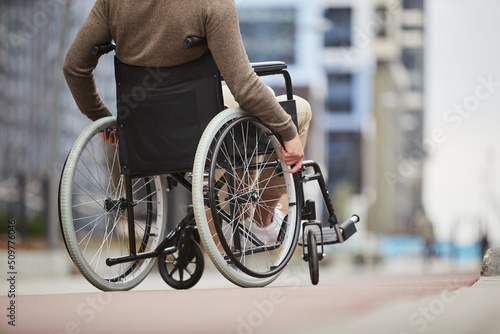 Unrecognizable disabled man in casual clothing using assistive device for personal mobility because of problem with legs