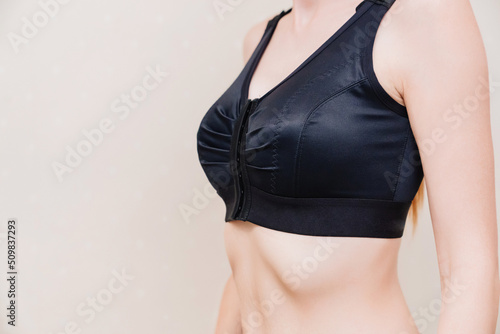 A young woman in black compression underwear after mammoplasty.