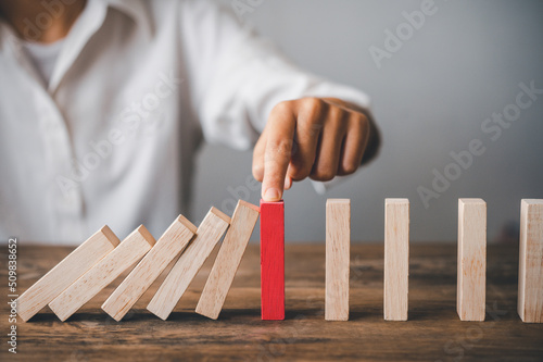 close-up hand The hand of a businessman who is stopping or preventing a falling block.Risk protection concept,Eliminating the risk..