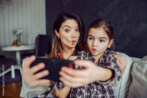 Mother and daughter making silly faces and taking a selfie.