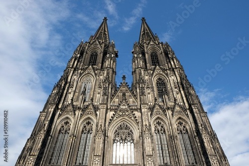 Der Kölner Dom im Stil der Gotik mit seinen Zwillingstürmen vor blauem Himmel im Sonnenschein an der Domplatte in Köln am Rhein in Nordrhein-Westfalen