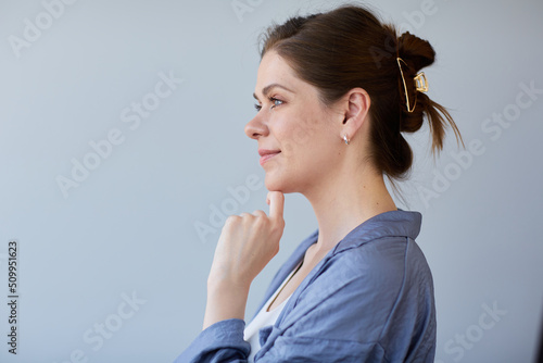 Smiling woman touching chin and looking away.