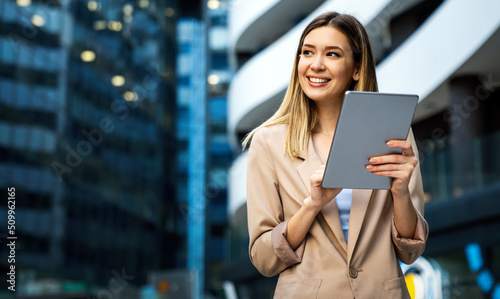 Portrait of a successful business woman using digital tablet in front of modern business building