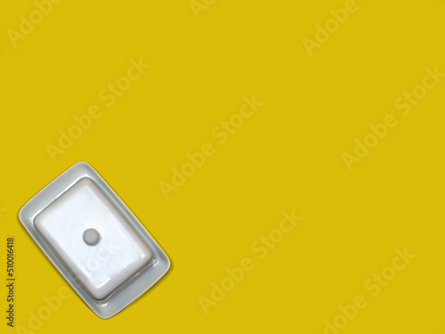 White china butter dish on bright yellow background with copy space. Flat lay