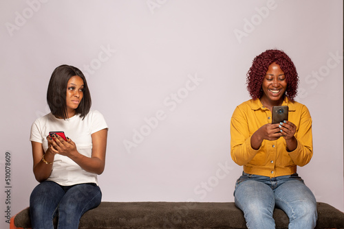 one girl happy another feels sad while checking their phones
