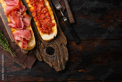 Spanish cured serrano ham with olive oil and toasted bread, on old dark wooden table background, top view flat lay, with copy space for text