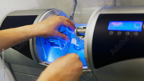 a dental technician installs a ceramic cube in a milling machine