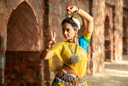 young Indian woman classical dancer doing dance pose outdoor, art and culture of india. 