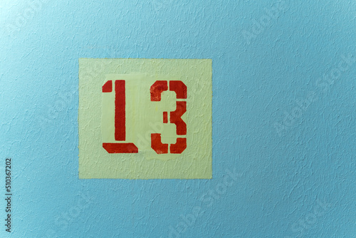 The number 13 red in a yellow square on a blue background