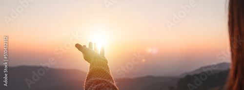 Young woman hand reaching for the mountains during sunset and beautiful landscape