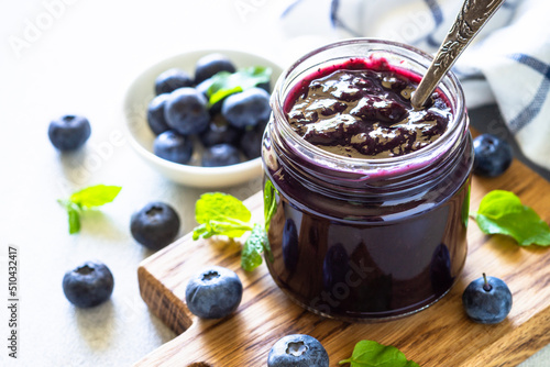 Blueberry jam in the glass jar with fresh berries.