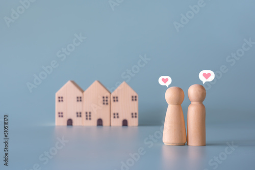 Small wooden faceless figures of human family members with heart icon and house. Property, hospitality, orphanage concept using wooden house and human model.