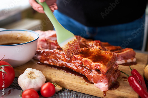 Brushing Pork Ribs with marinade sauce on Wooden Cutting Board