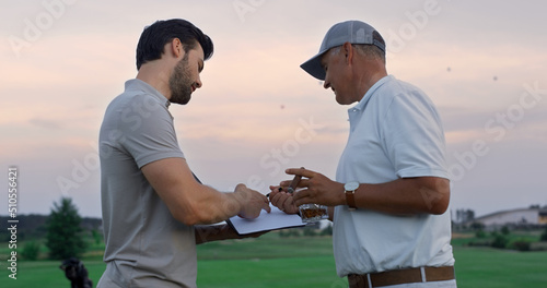 Active sportsmen discuss golf on sunset course. Two golfers talk at country club