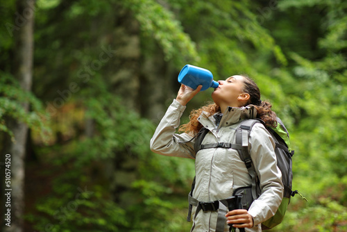 Trekker drinking water from canteen in a forest