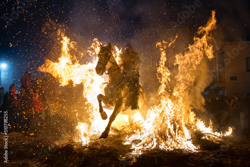 horses with their riders jumping bonfires as a tradition to purify animals..