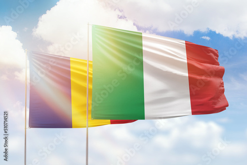 Sunny blue sky and flags of italy and romania