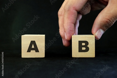Plan B or backup and contingency plan in business concept. Hand choosing B versus A in wooden blocks in dark black background. 