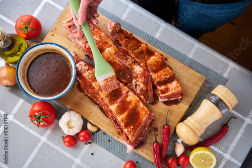 Brushing Pork Ribs with marinade sauce on Wooden Cutting Board