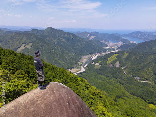 ドローンから空撮した三重便石山の象の背の岩に立つ人の写真