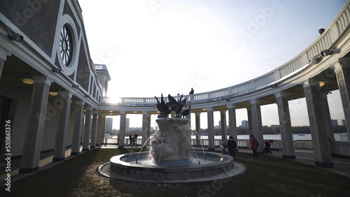 Beautiful fountain on background of colonnade. Action. Fountain inside colonnade on background clear Sunny sky. Beautiful details of architectural building of Northern river station in Moscow