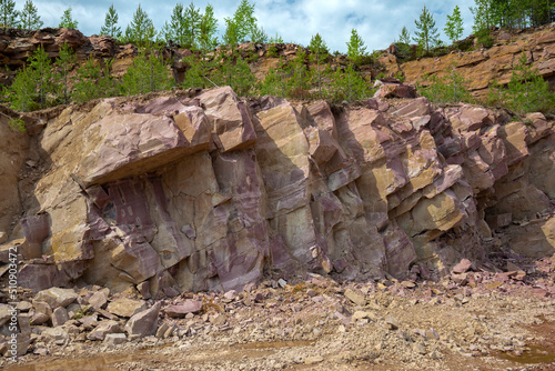 A section of crimson quartzite rock in an old quarry. Kvartsitny village, Karelia