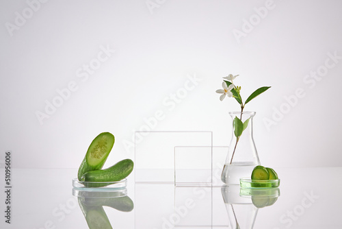 Front view of transparent podium with laboratory equipment and cucumber in white background science content