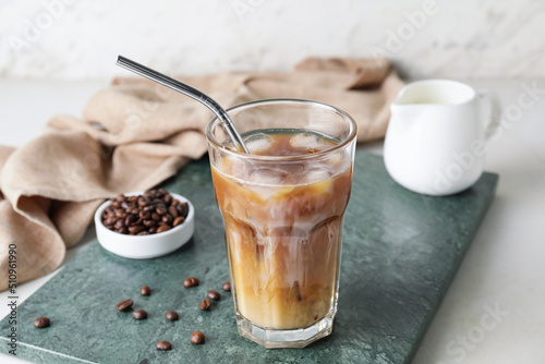 Board with glass of cold brew coffee on white table