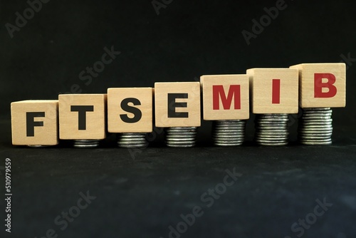 Italian Italy stock market economy growth and recovery concept. FTSE MIB index in wooden blocks with increasing stack of coins in black background.