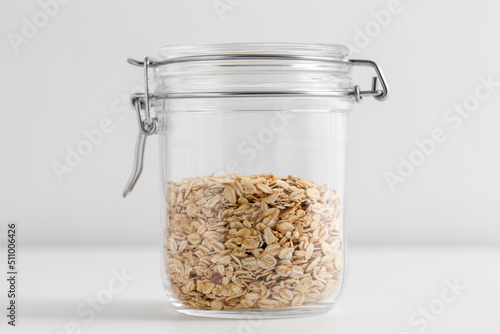 food, healthy eating and diet concept - jar with oat flakes on white background