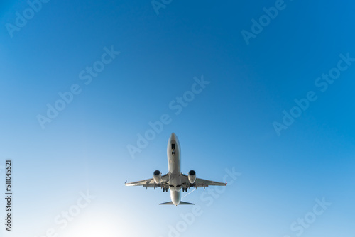 Close-up view from below of a departing plane with landing gear on a blue sky background on a sunny day, copy space