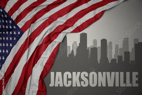 abstract silhouette of the city with text jacksonville near waving national flag of united states of america on a gray background.