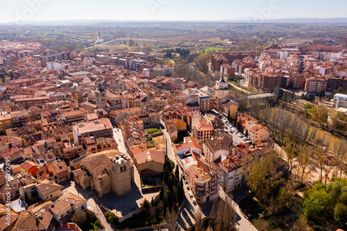Drone view of Aranda de Duero cityscape on river banks in spring overlooking terracotta tiled roofs of houses, Spain..